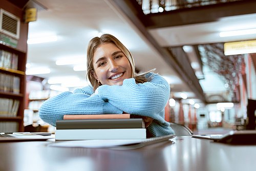 Portrait einer Frau in Universitätsbibliothek, Blick in die Kamera