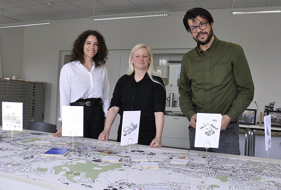 Drei Menschen stehen vor einem Tisch, auf dem eine Karte von Wuppertal ausgebreitet liegt.