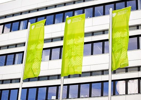 Grüne Fahnen vor einem Uni-Gebäude.